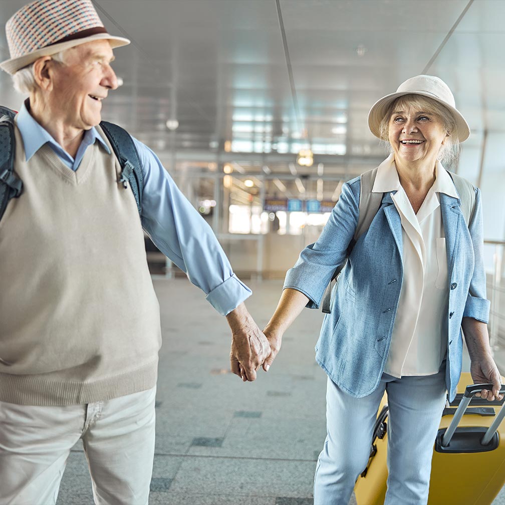 smiling senior couple holding hands at the airport ready to go on vacation after budgeting for retirement holland oh